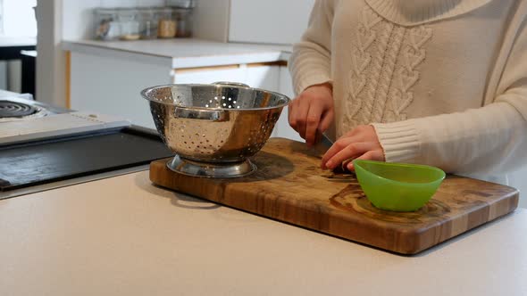 Woman chopping a vegetable with knife on kitchen worktop