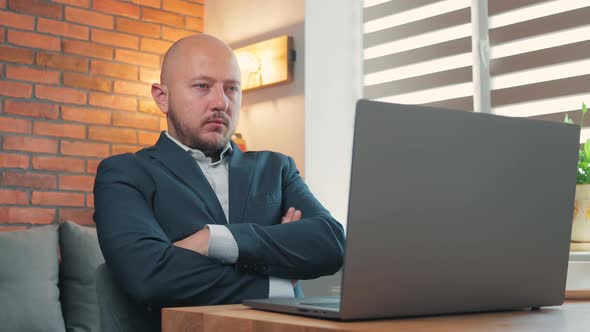 Portrait of young man in the suit looking at laptop screen and shaking head, gesturing no