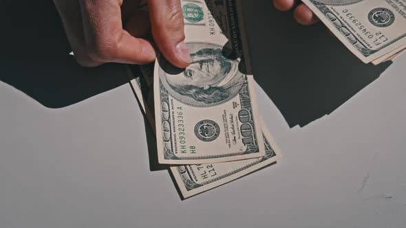 Male Hands Counting Old Hundred Dollar Banknotes on a White Table