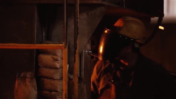 Worker wearing a Mask working with a Flaming Torch at a Steel Mill.