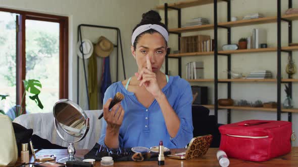 Portrait of mixed race female vlogger applying make up at home