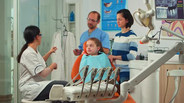 Stomatologist Holding Plaster Model of the Mandible Speaking with Girl Patient