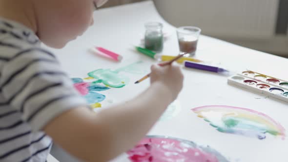 Sideview Baby Boy Child Painting Fruits and Rainbow Using Brush and Paints Home