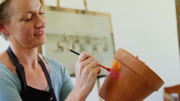 Woman painting pot in drawing class