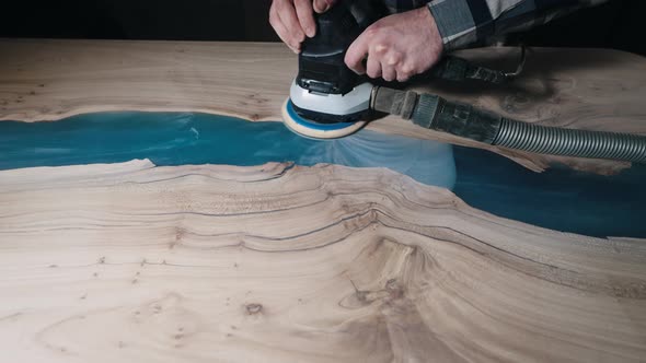 The Carpenter Processes the Surface of a Wooden Tabletop with a Grinder