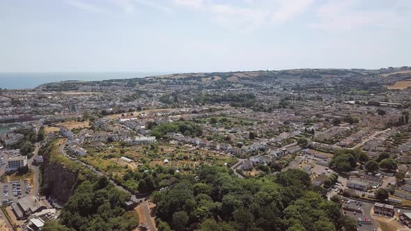 Aerial view of town and coastline in Brixham, England. Sky view of homes, hotels, and resorts in Eng