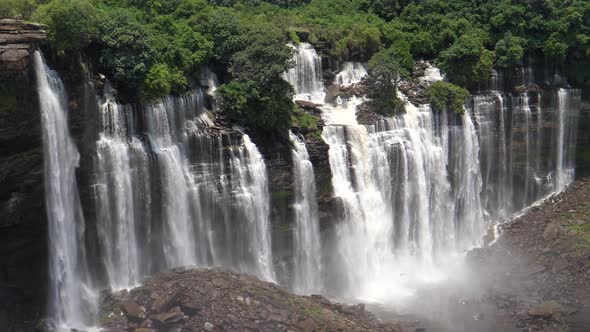 Pan from massive streams of water falling down at the Kalandula Falls