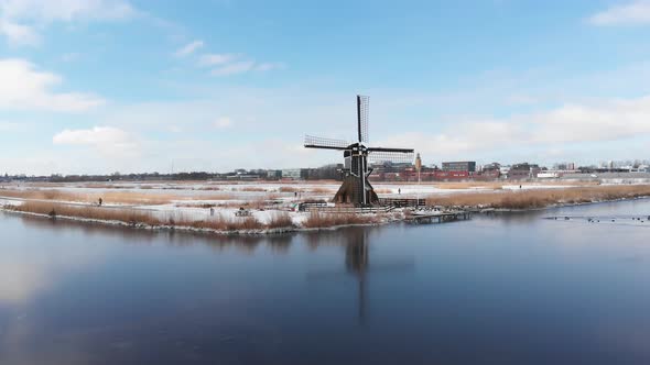 Iconic Dutch windmill in winter snow scene landscape, aerial view