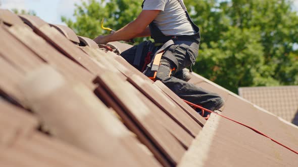 Repairman, fixing the tiles on rooftop of hut. Slow motion side view Concept of professionalism, job