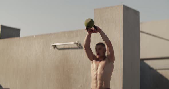 Sportsman Exercising with Kettlebell Outside Concrete Building