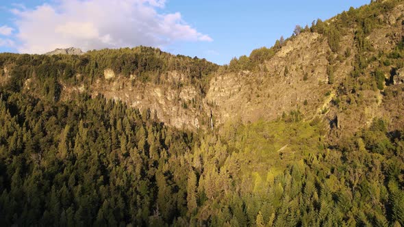 Aerial dolly in over mountains covered in cypress woods and Corbata Blanca waterfall in background a