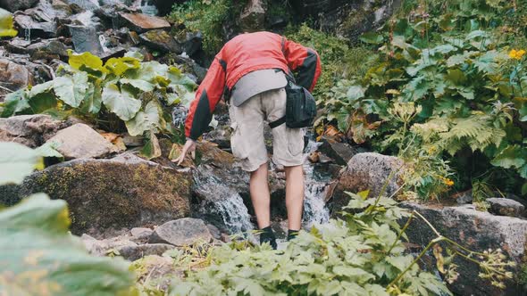 Tourist Collects Water in a Plastic Bottle From a Mountain Stream. Hiking Adventure