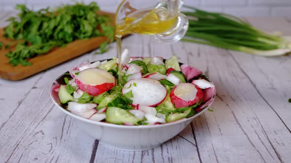 Hands Chef Pouring Olive Oil in a Vegetable Salad with Radish Cucumber Greens