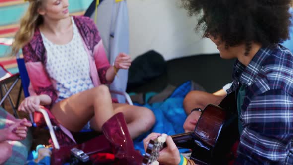 Man playing guitar for his friends at a music festival 4k