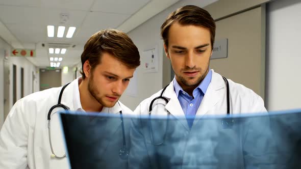 Doctors examining x-ray report in corridor