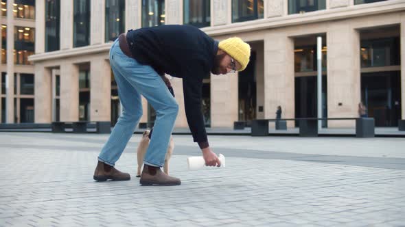 Man Bending Down and Spraying with Detergent Pet Pee on Pavement Outdoors