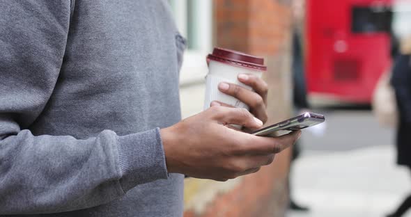 Man using smartphone and holding coffee to go