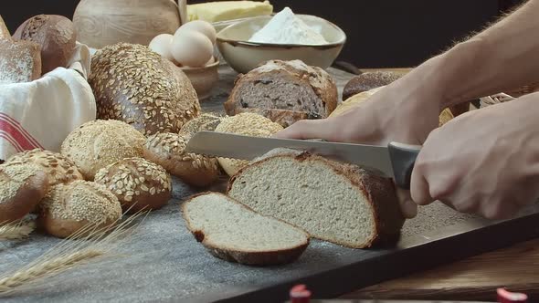 Hands Cutting the Baked Dutch Bread on the Table