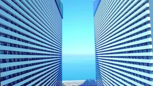 the drone flies between two buildings with glass windows.