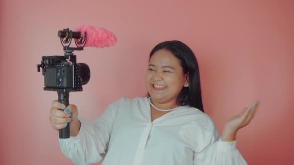Young Woman Vlogger Recording Broadcast in Slow Motion on a Pink Background