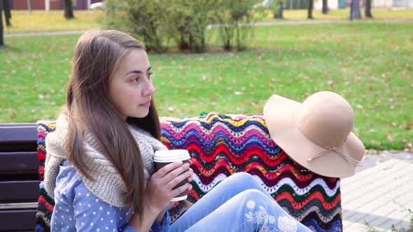 Beautiful Girl Sitting on a Bench in a Sunny Park in Autumn