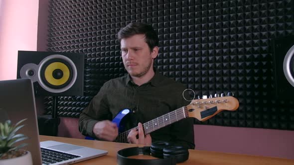 Male Learning Play Guitar at Home Using Online Lessons