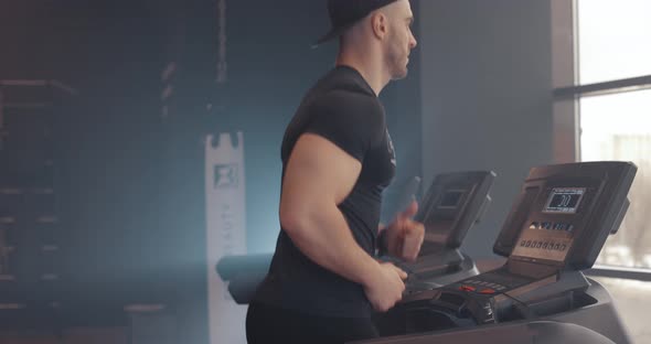 Athletic and Muscular Handsome Man in Sportswear Running on Treadmill at Gym Side View Slow Motion