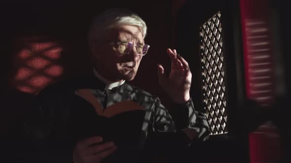 Aged Priest Sitting in Confessional