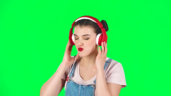 Girl Dancing and Singing in Big Red Headphones on Green Screen at Studio, Slow Motion