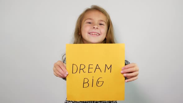 Smiling teenage girl shows into the camera phrase dream big