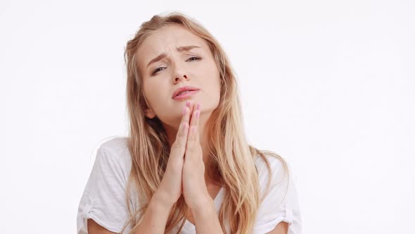 Young Beautiful Caucasian Blonde Girl Begging Saying Please Praying on White Background in