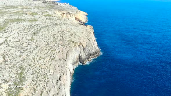 Drone shot over rocks and Cliffs in the Mediterranean sea of Malta.