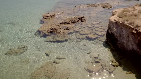 Aerial view of beach shore with rocks and very calm water in Greece.