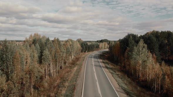 Asphalt road with traffic cars between forest in Ural