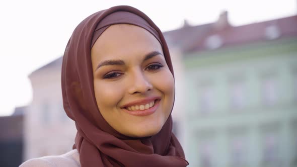 A Young Beautiful Muslim Woman Smiles at the Camera in a Street in an Urban Area Colorful Buildings