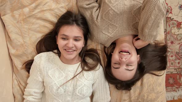 Portrait of Happy Smiling Girls Talking While Relaxing on Bed at Home
