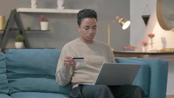 African Woman Making Online Payment on Laptop on Sofa