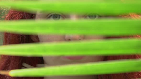 Girl behind a palm tree leaf