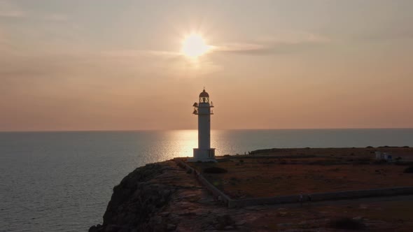 Amazing Sunset reflects of serene ocean waters with silhouetted lighthouse and ocean cliffs, drone a