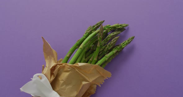 Video of fresh asparagus wrapped with white ribbon and copy space over lilac background
