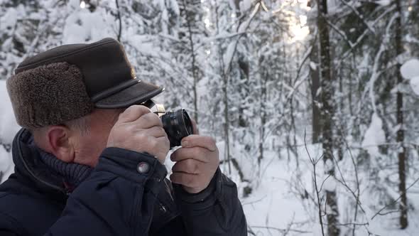 Elderly Man Is Photographing Forest at Winter Walking in Snowy Woodland at Daytime