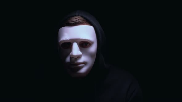 Man in Terrible Face Mask Staring at Camera Against Dark Background, Terrorism