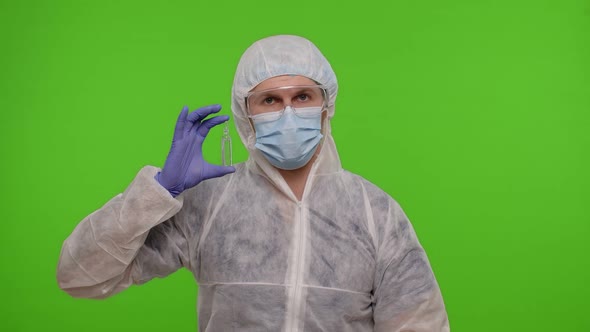 Doctor in PPE Suit with Coronavirus Vaccine Ampoule and Credit Card in Hands on Green Chroma Key