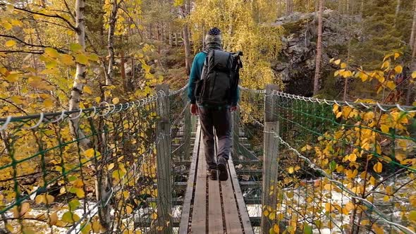Man Walks on the Suspension Bridge in Oulanka National Park at Autumn in Finland