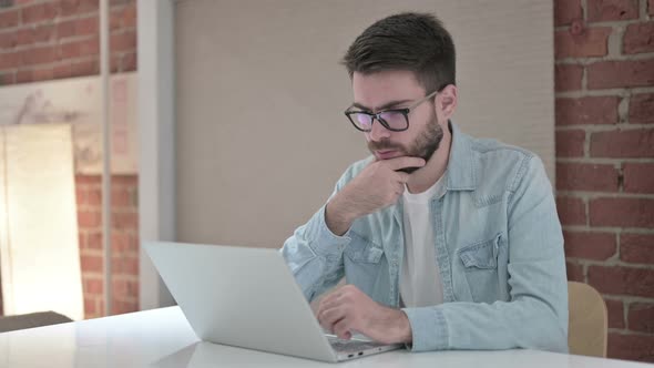 Young Professional Male Designer Thinking and Working on Laptop 