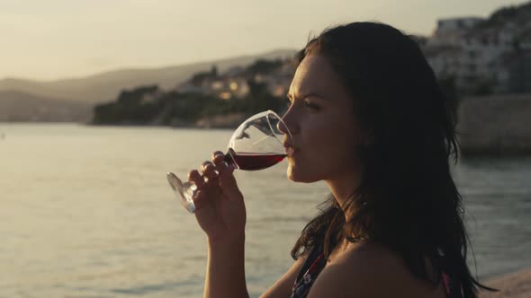 Girl with a Glass of Wine By the Ocean is Happy on Vacation