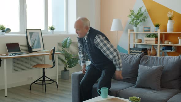 Slow Motion of Senior Man Standing Up From Sofa Feeling Backache at Home