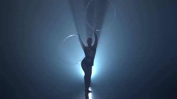 Gymnast Tricks with Hoops on Her Hands and Lifts Her Leg in the Air