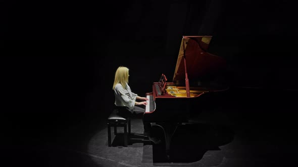 Blonde Behind a Red Piano on a Dark Stage