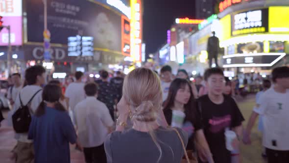 Blonde Hair Girl Crossing The Road In Asia, China, crowded crossroads, night life, neon lights